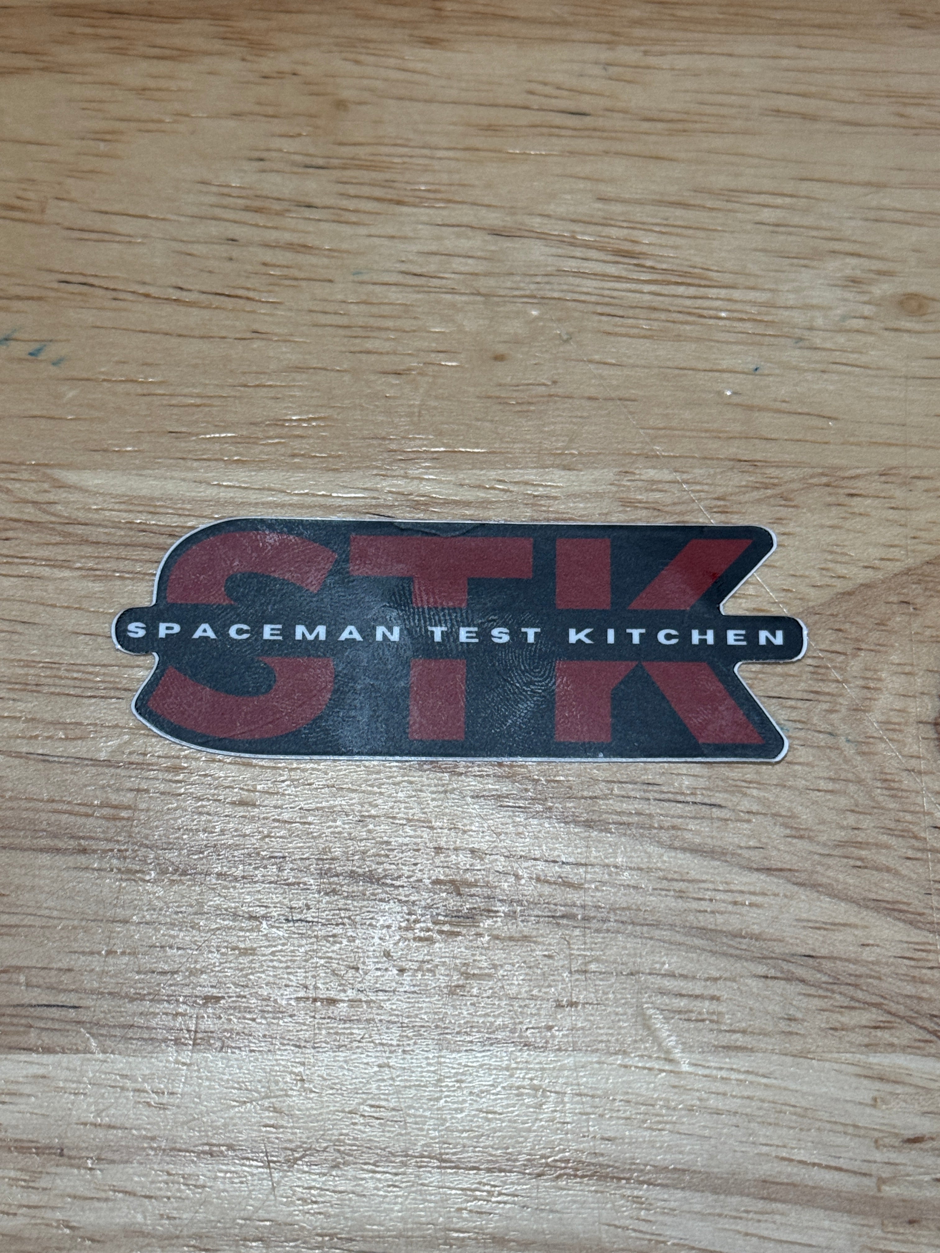 STK Spaceman Test Kitchen logo on a wooden surface